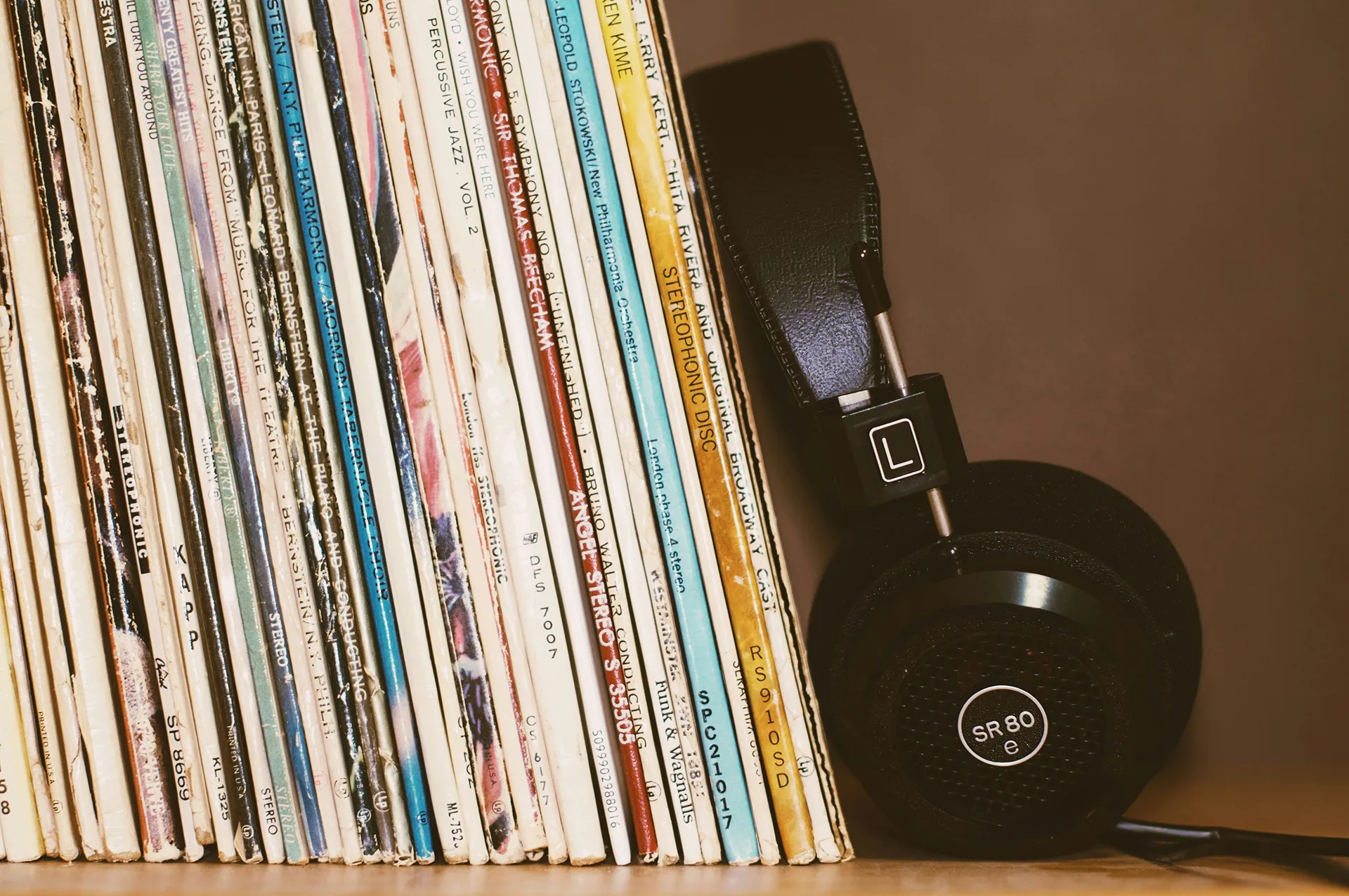 Headphones resting next to a stack of vinyl records