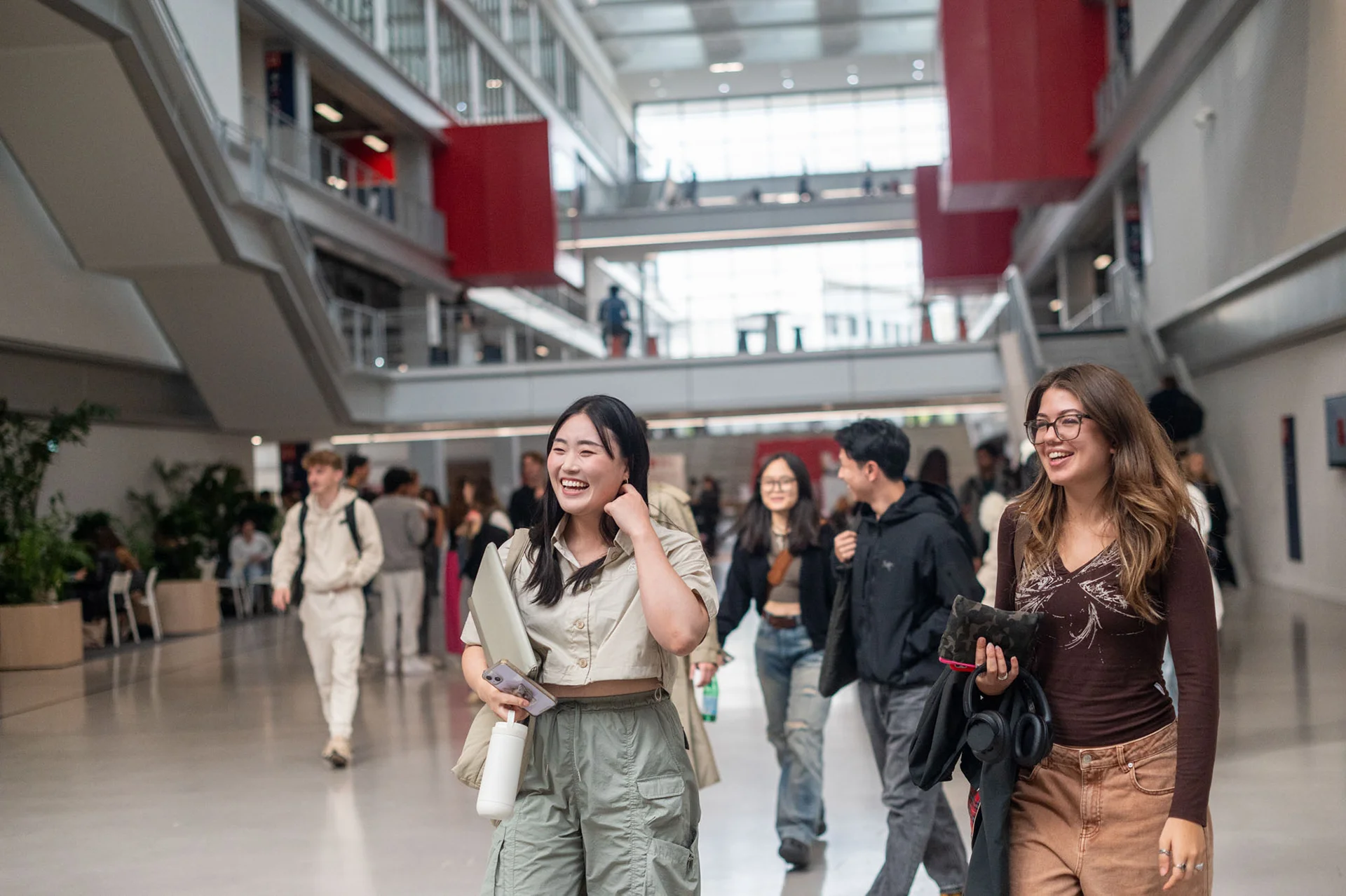 Étudiants dans le hall principal du campus d'emlyon à Lyon, illustrant la vie étudiante, les déplacements quotidiens et l’architecture contemporaine d’une école de management.