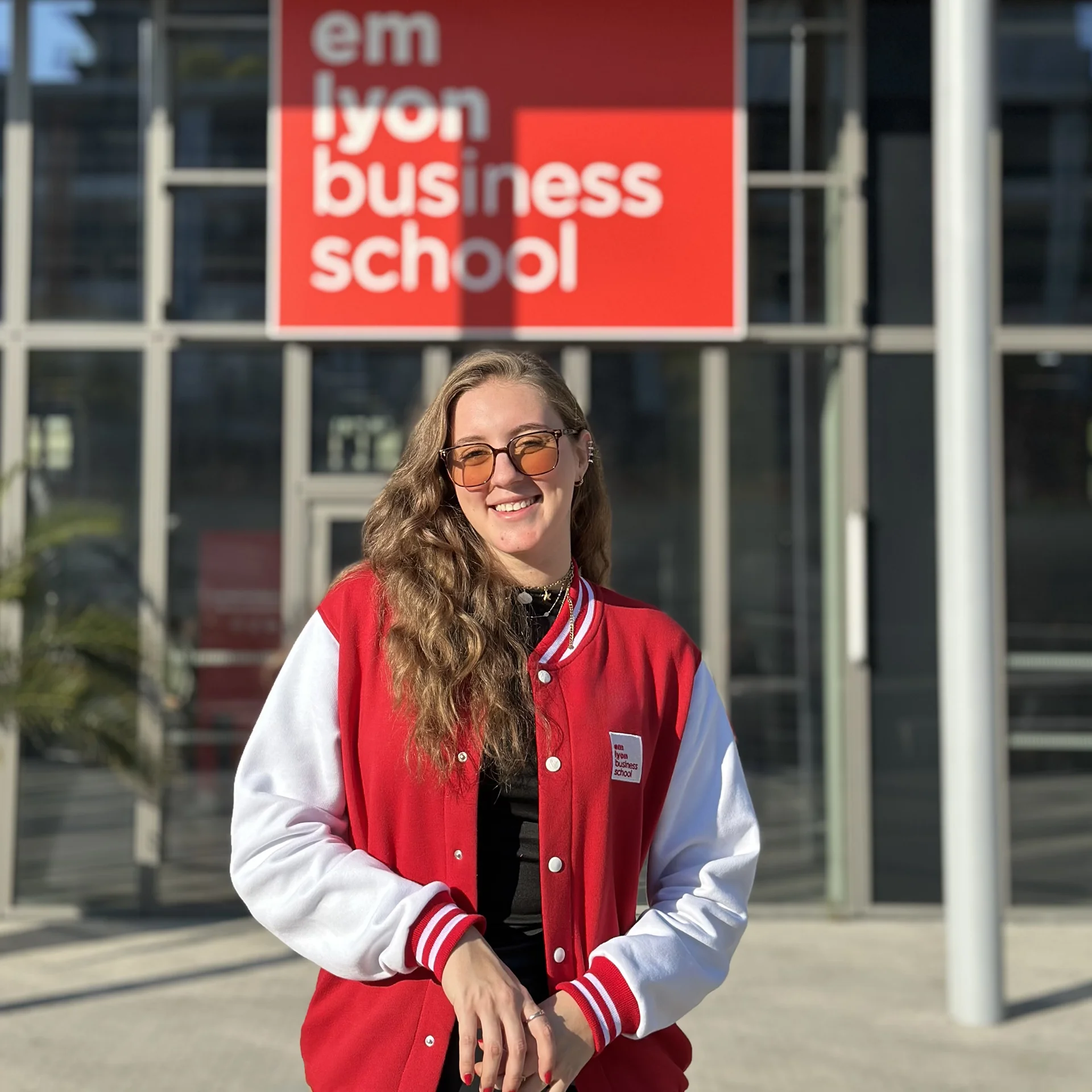 Elisa Anastasio (étudiante du MSc in Healthcare Innovation &amp; Data Science d'emlyon business school) posant devant l’entrée du campus de Lyon d'emlyon business school.