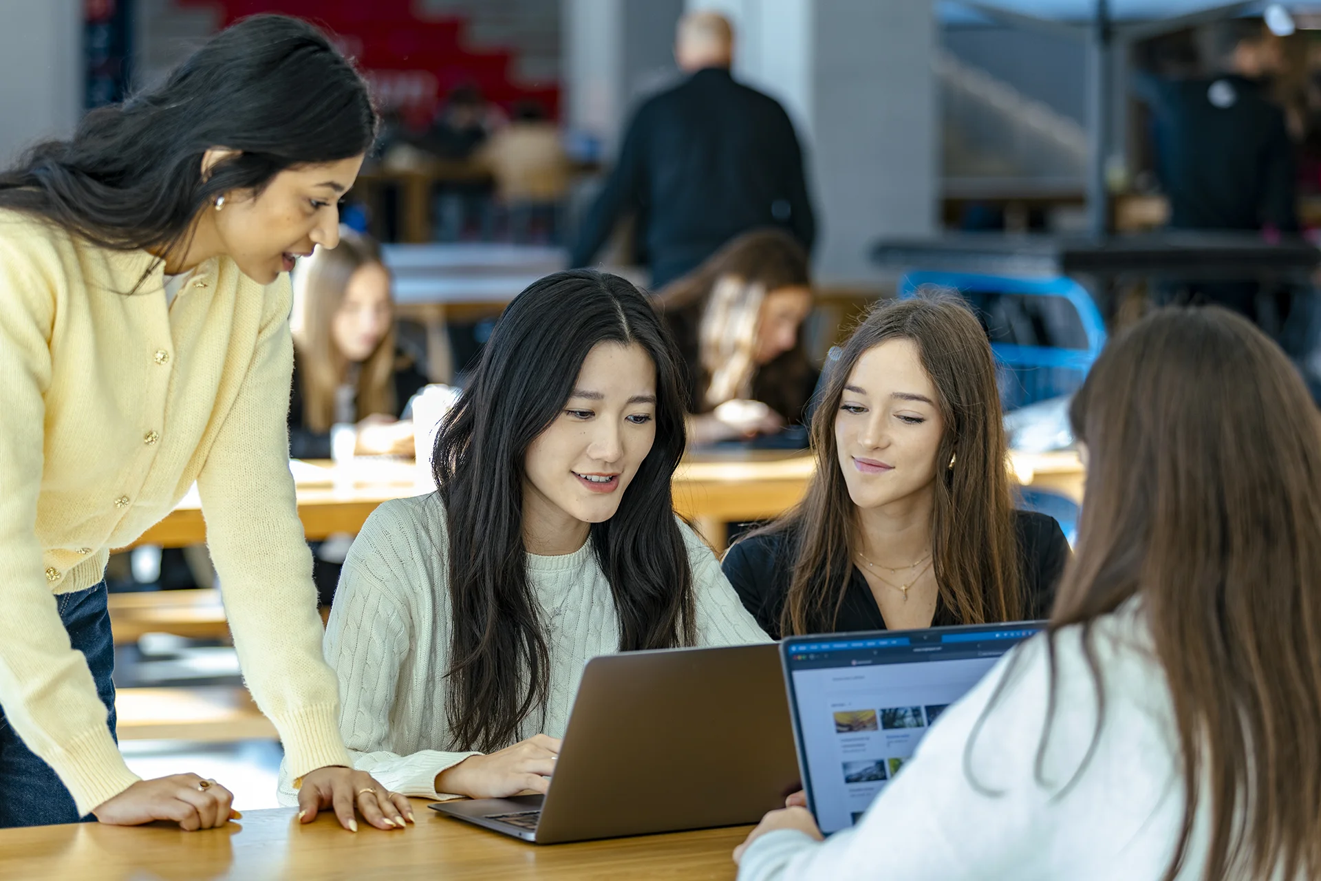 Group of emlyon students collaborating on a laptop in a shared workspace on campus