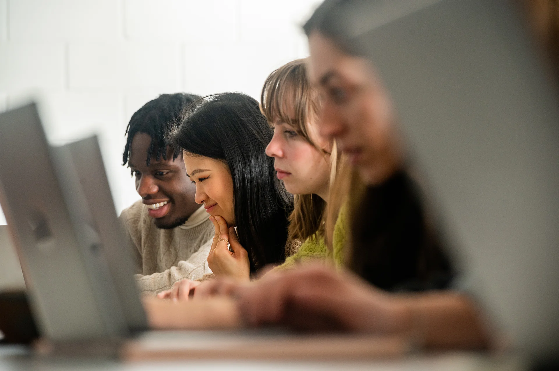 Étudiants travaillant sur leurs ordinateurs portables dans un espace d’apprentissage moderne, illustrant la vie académique et les travaux de groupe au sein d’une école de management.