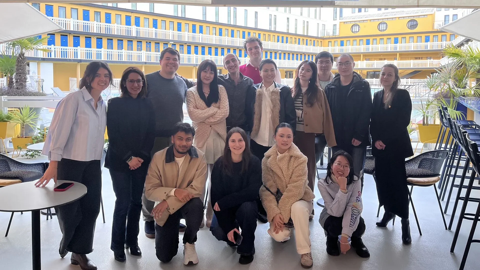 Un groupe d'étudiants d'emlyon se tient devant une œuvre d'art moderne colorée à Station F, un espace d'innovation réputé à Paris. L'ambiance est dynamique, et le décor reflète l'esprit entrepreneurial de l'incubateur. Les étudiants présentent une atmosphère de camaraderie, capturant un moment mémorable lors de leur visite.