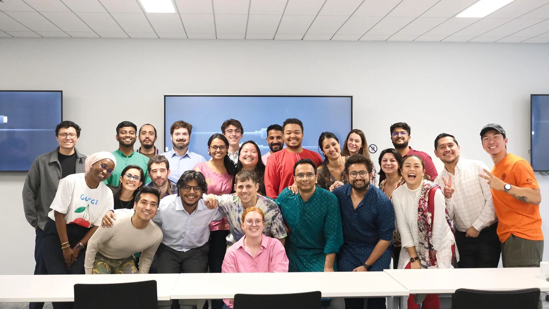 Photo de groupe lors d’un événement d’entreprise, avec une équipe réunie dans une salle de réunion moderne, devant deux écrans muraux.
