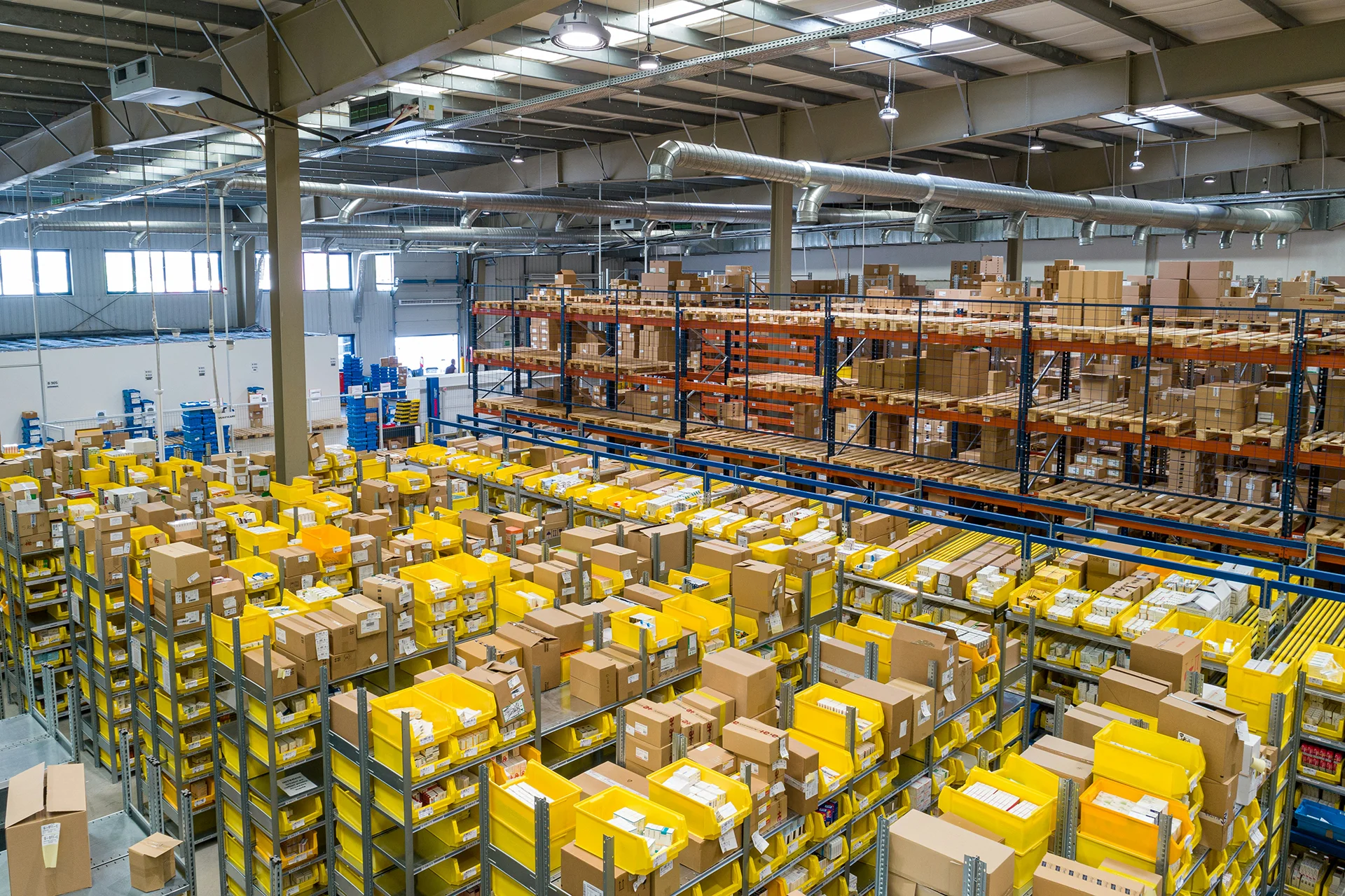Logistics warehouse with industrial shelving filled with packages and yellow storage bins in a distribution center.