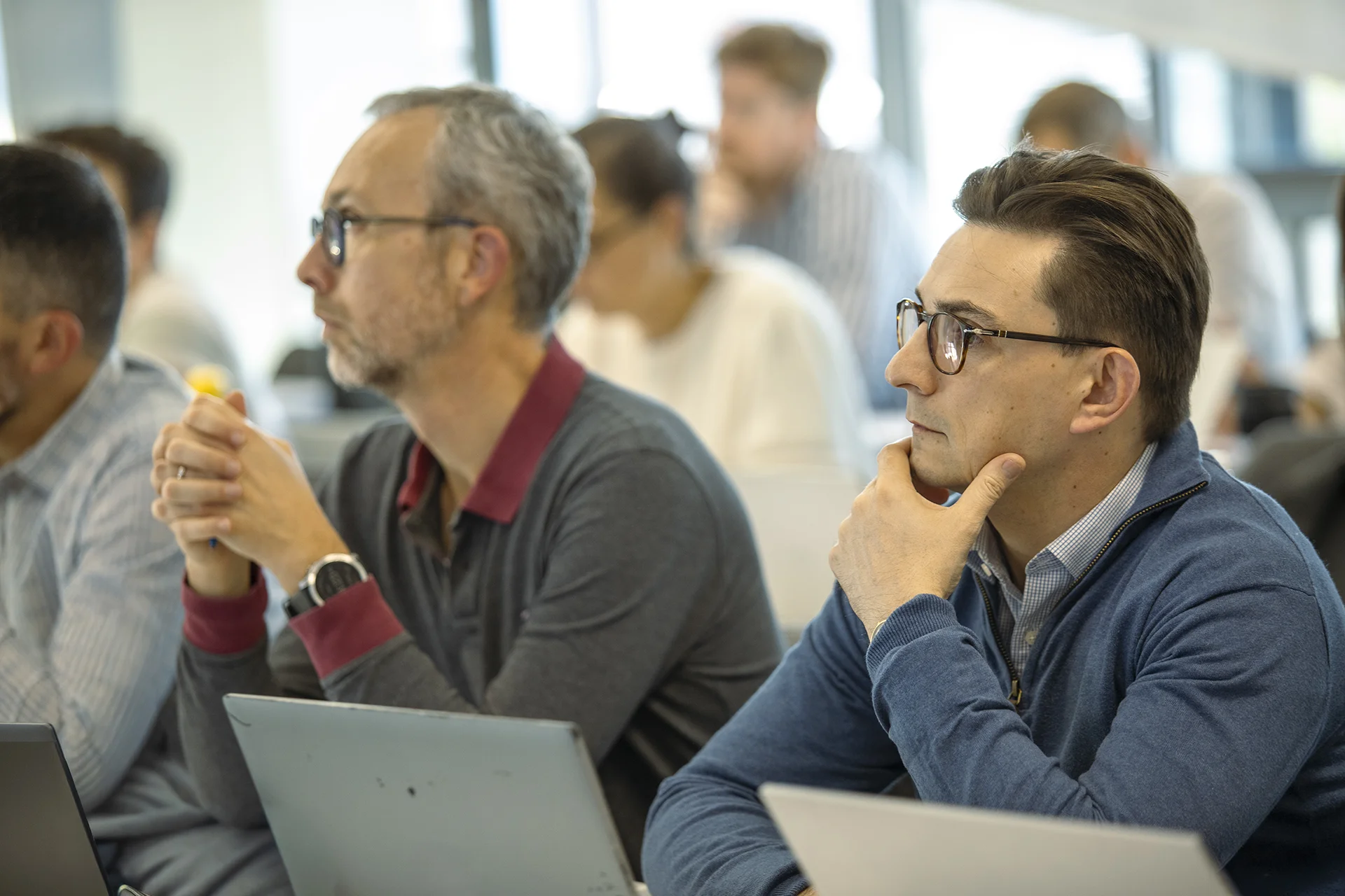 Personnes assises et concentrées, utilisant des ordinateurs portables lors d’une session de formation ou de certification en salle.
