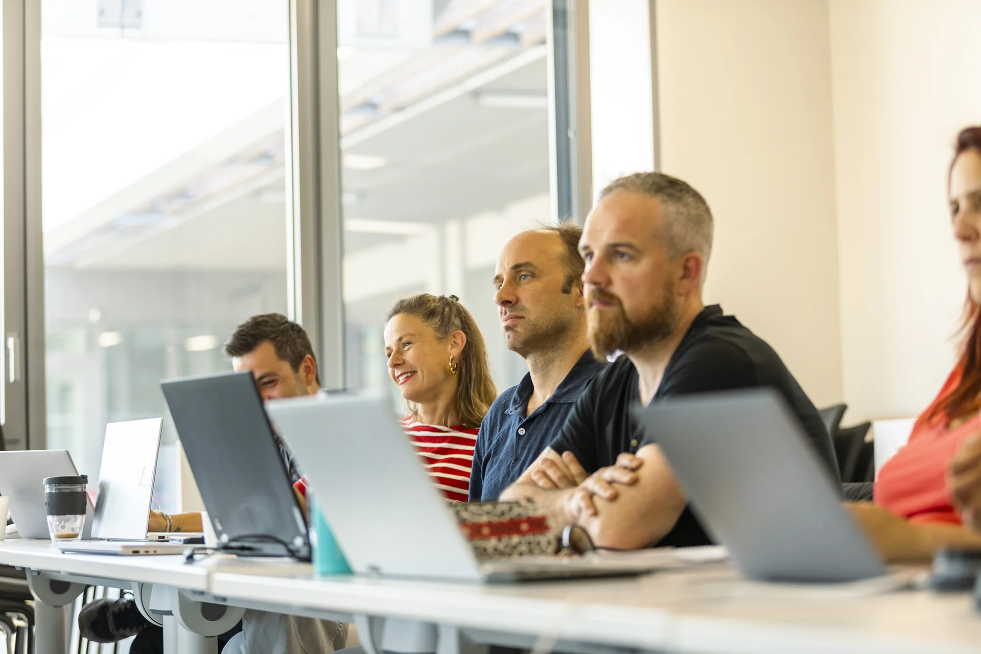 Participants in the E2MG program at emlyon business school attending a class and working on laptops in a bright classroom.