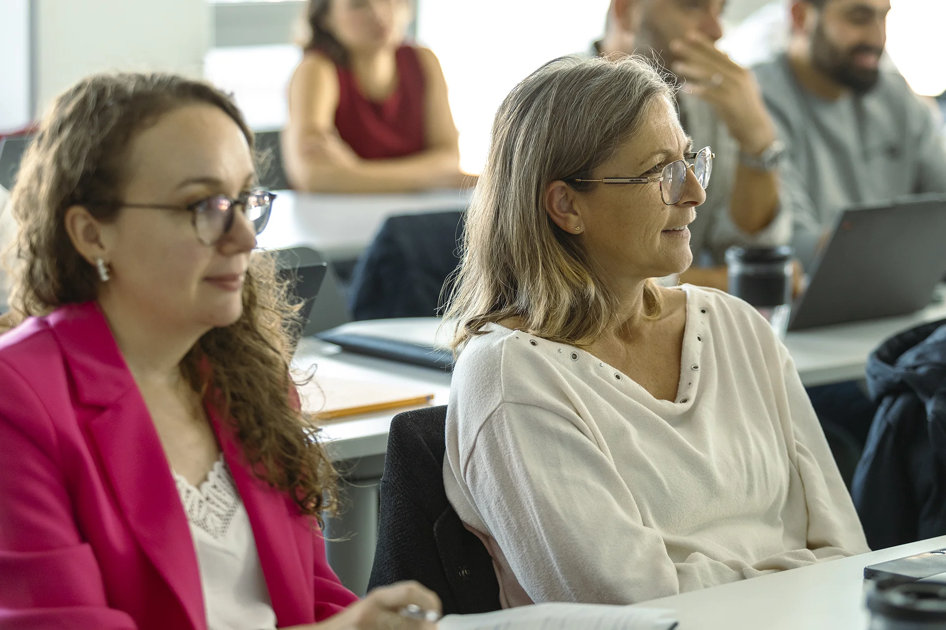 Executive MBA participants at emlyon seated in a classroom, listening attentively during a course session.