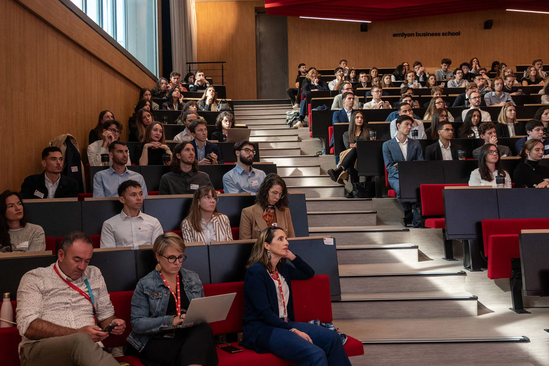 Auditorium universitaire rempli de participants assis en gradins, assistant à une conférence ou une présentation.