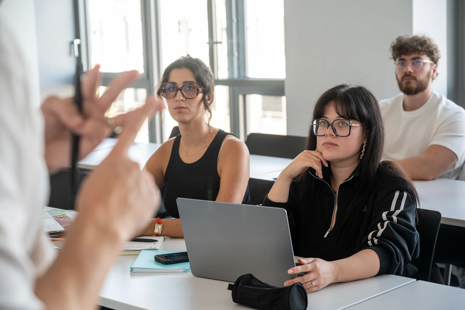Personnes assises dans une salle de formation, écoutant une intervention et utilisant un ordinateur portable à une table.