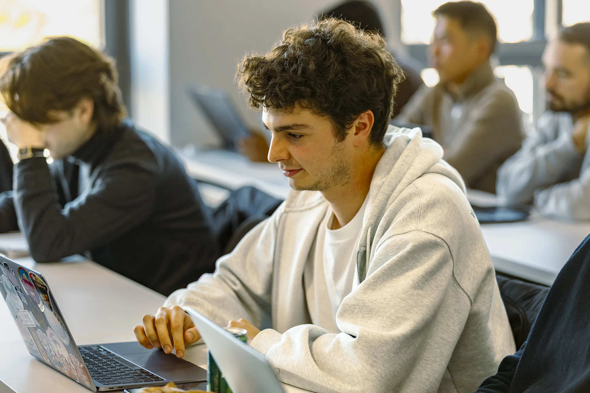 Students seated in a classroom, working on laptops during a class session.