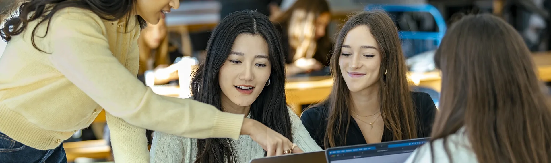 Group of people working together around laptops in a collaborative learning or work environment.