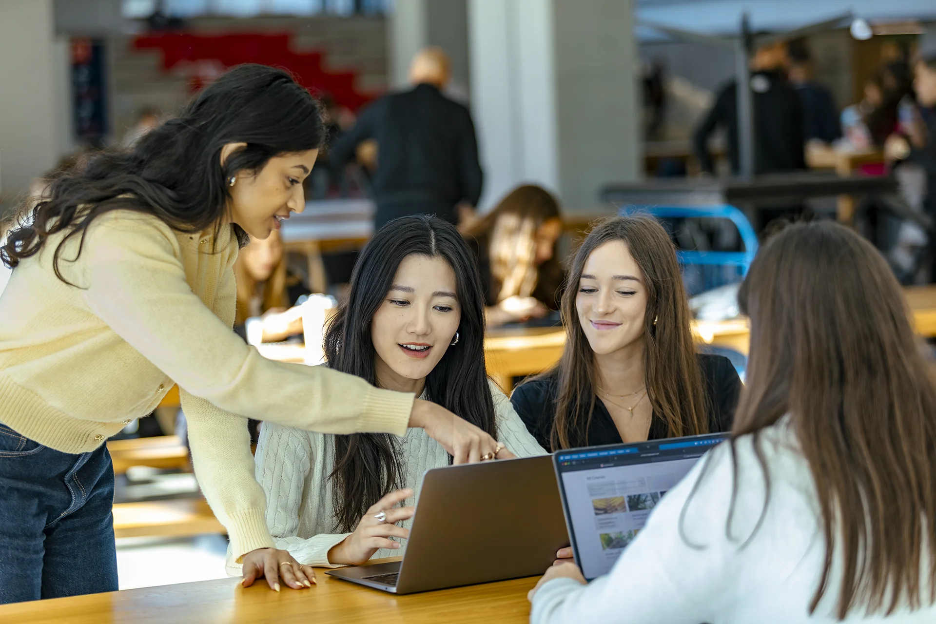 Groupe de personnes travaillant ensemble autour d’ordinateurs portables dans un environnement d’apprentissage ou de travail collaboratif.