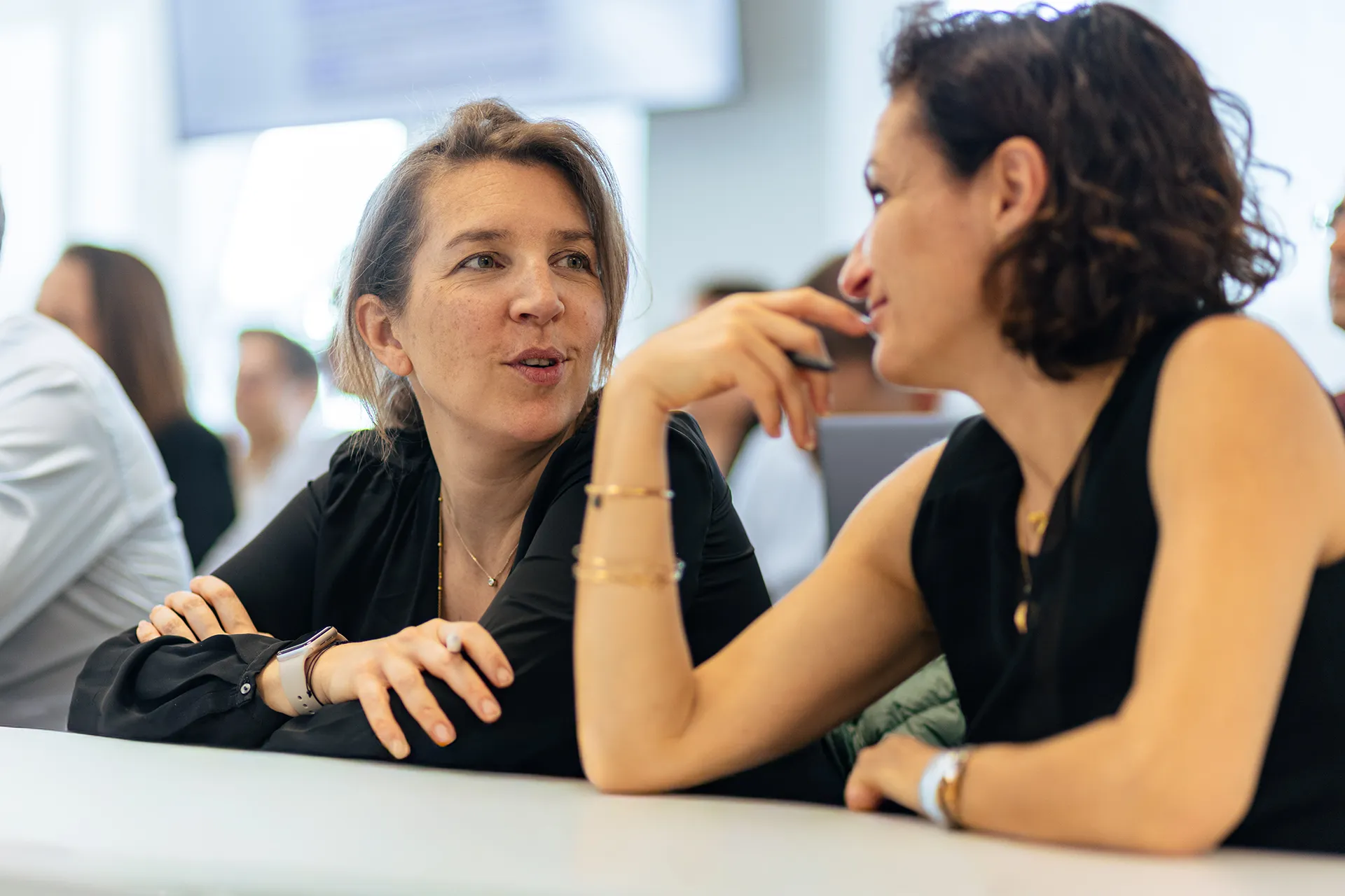 Deux personnes discutent à une table pendant une session de travail en groupe dans une salle de formation.