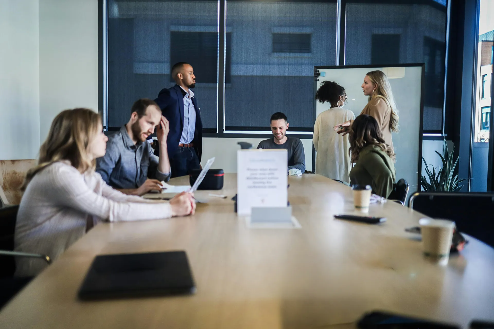 Plusieurs personnes réunies autour d’une grande table dans une salle de réunion, avec ordinateurs portables et documents.