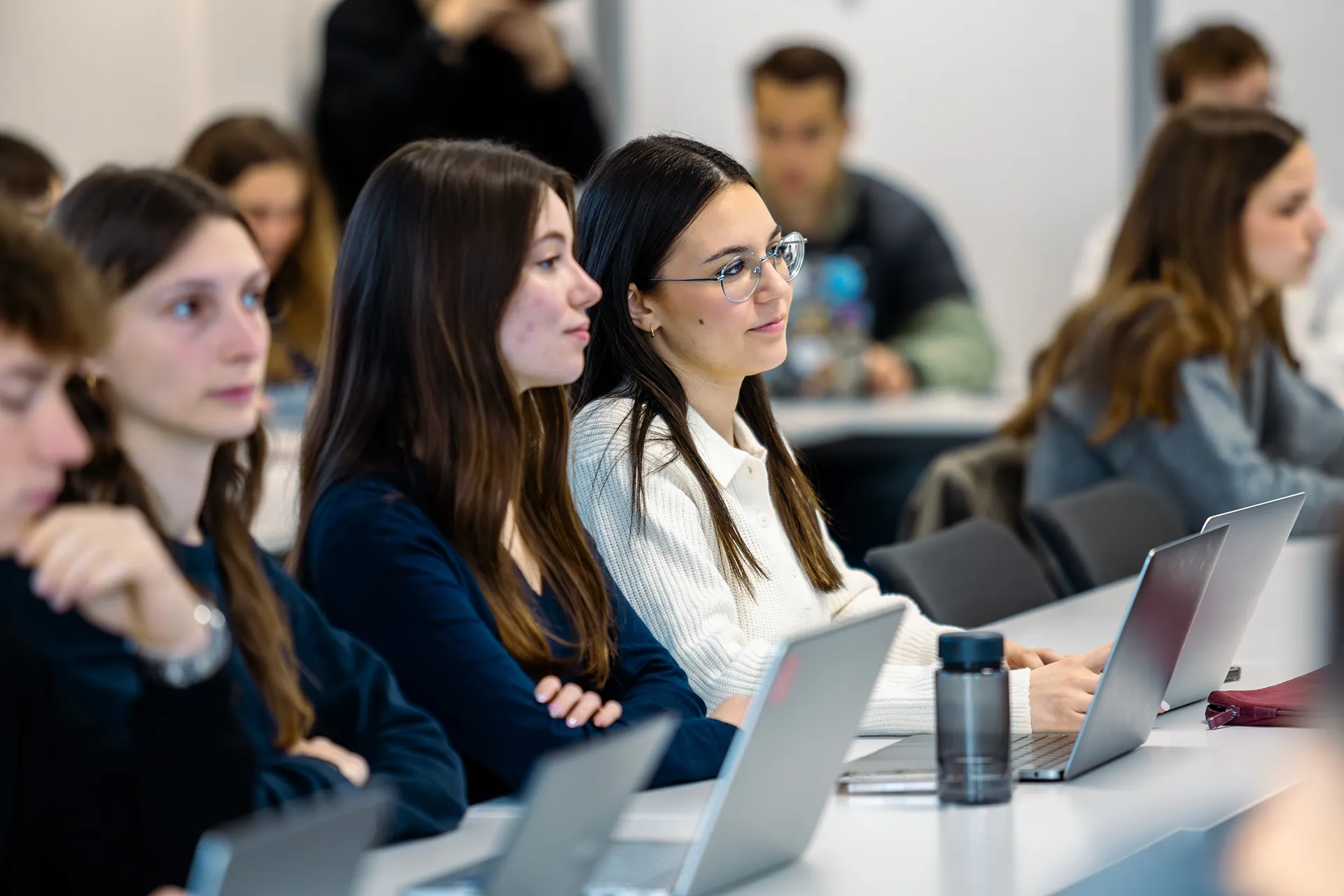 Étudiants assis dans une salle de cours, utilisant des ordinateurs portables lors d’une session de formation universitaire.