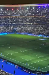 Vue du terrain de rugby avec des lumières scintillantes dans un stade rempli de supporters.
