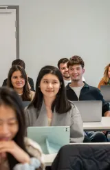 Salle de classe avec des étudiants emlyon assis à des bureaux, utilisant des ordinateurs portables et des tablettes pendant un cours.