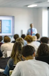 MSc students at emlyon business school attending a lecture in a classroom, using laptops while a presentation is displayed on screen.