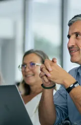 Participants de l’Executive MBA à emlyon écoutant attentivement pendant un cours de business, avec des ordinateurs portables visibles sur les tables de la salle de classe.