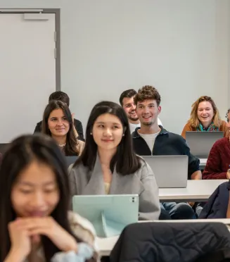 Salle de classe avec des étudiants emlyon assis à des bureaux, utilisant des ordinateurs portables et des tablettes pendant un cours.