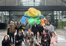 The image features a group of emlyon students standing in front of a modern and colorful art installation at Station F, an iconic center dedicated to innovation and entrepreneurship. The artwork, with its bold shapes and vibrant colors, serves as a backdrop for a moment of camaraderie among the students. The warm and dynamic atmosphere of Station F is evident, illustrating the teamwork and creativity inherent in this stimulating environment.