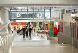 Vue intérieure du campus emlyon avec des étudiants circulant dans les espaces communs, entre amphithéâtre, services étudiants et zones de travail collaboratif.