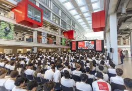 Étudiants participant à une réunion de rentrée dans le grand atrium du campus emlyon, présentant les informations d’accueil et de vie académique.