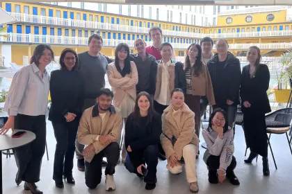 Un groupe d'étudiants d'emlyon se tient devant une œuvre d'art moderne colorée à Station F, un espace d'innovation réputé à Paris. L'ambiance est dynamique, et le décor reflète l'esprit entrepreneurial de l'incubateur. Les étudiants présentent une atmosphère de camaraderie, capturant un moment mémorable lors de leur visite.
