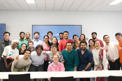 Group photoof the IMBA group, showing the team gathered in a modern meeting room with two wall-mounted screens.