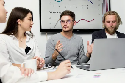Réunion d’équipe autour d’un ordinateur avec présentation de données et graphiques lors d’un atelier de travail collaboratif.