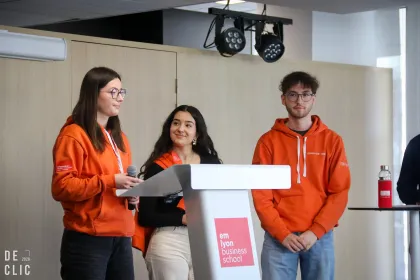 Students from the NOISE association at emlyon business school during the signing of the CSR charter, standing around a podium at the event.