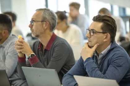 Personnes assises et concentrées, utilisant des ordinateurs portables lors d’une session de formation ou de certification en salle.