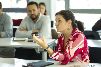Executive MBA participant speaking during a group discussion at emlyon, with other participants seated in a classroom environment.