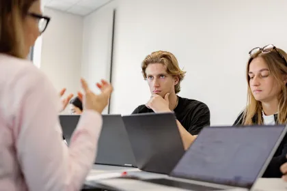 emlyon students working together on laptops during a collaborative study session in a classroom.