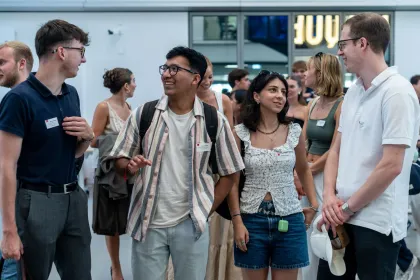 Group of people wearing name badges walking and conversing inside the emlyon campus in Lyon during a student event.