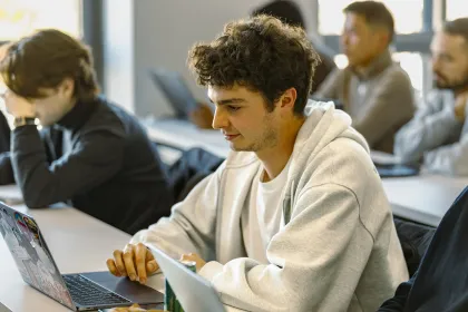 Students seated in a classroom, working on laptops during a class session.