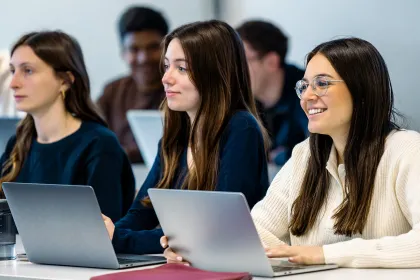 Étudiants assis à des tables utilisant des ordinateurs portables pendant un cours dans une salle de classe d’emlyon.