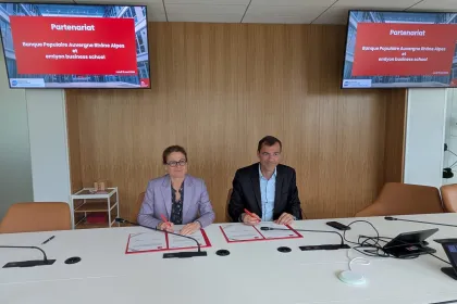Isabelle HUALT and Daniel KARYOTIS  standing in front of partnership announcement screen