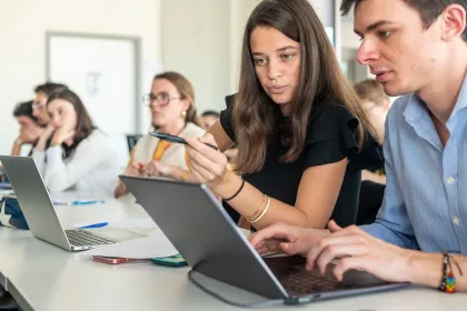 Signature officielle d’un partenariat entre mc2i et emlyon business school lors d’une réunion, avec logos affichés sur écran en arrière-plan