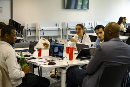 Groupe de collaborateurs travaillant sur ordinateurs portables autour d’une table lors d’un atelier en salle de formation