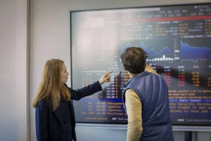 Professionals reviewing financial charts and analytics on a digital screen in a classroom or business analytics setting