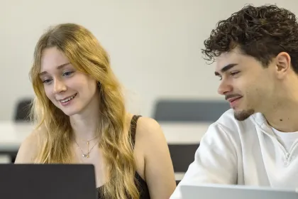 Étudiants travaillant ensemble sur ordinateur dans un environnement d’apprentissage collaboratif au sein d’un programme de formation en management.