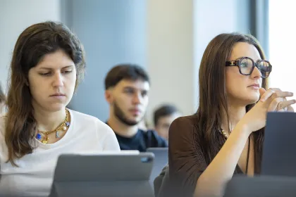 Étudiant en salle de cours échangeant avec d’autres participants lors d’une formation en école de commerce.