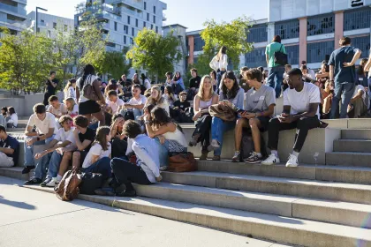 Étudiants sur les gradins du campus emlyon, participant à la vie étudiante et aux échanges de rentrée dans un environnement universitaire moderne.