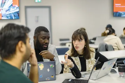 Students collaborating around laptops during a class session at a business school in Paris.