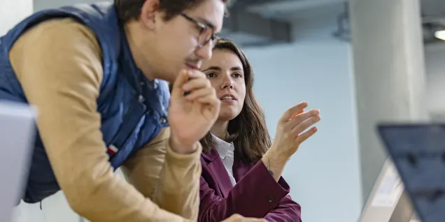 Two students from emlyon business school discussing in front of a computer screen.