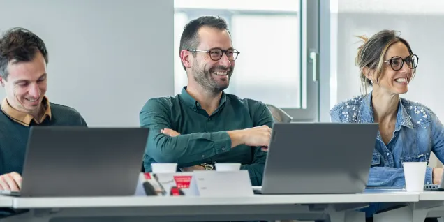 Participants of the emlyon executive program attending a training session, working together on laptops in a modern classroom