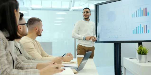 Professional presentation with a speaker explaining performance charts to a team during a meeting in a modern conference room.