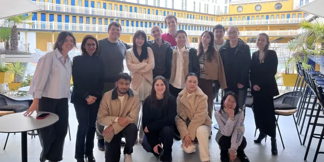 Un groupe d'étudiants d'emlyon se tient devant une œuvre d'art moderne colorée à Station F, un espace d'innovation réputé à Paris. L'ambiance est dynamique, et le décor reflète l'esprit entrepreneurial de l'incubateur. Les étudiants présentent une atmosphère de camaraderie, capturant un moment mémorable lors de leur visite.