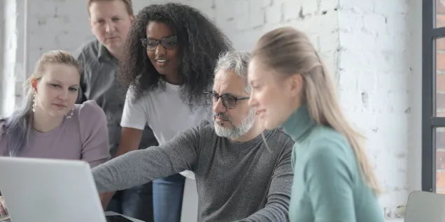 Équipe collaborant autour d’un ordinateur portable dans un bureau lumineux